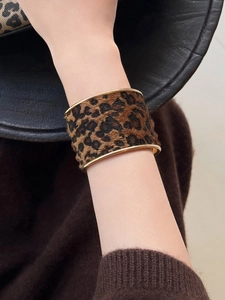 Gros plan sur un bracelet léopard vintage avec bordure dorée porté au poignet