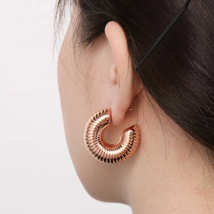 Close-up of model wearing 18K gold-plated C-shape earrings with a textured twist design
