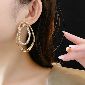 Detail of gold double-hoop earrings with sparkling rhinestones worn on earlobe