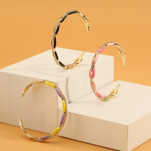 Detail of colorful enamel gold bracelets with zircon accents on geometric pedestals