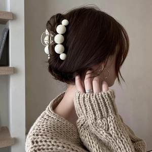 Grande pince à cheveux élégante avec perles blanches montrée sur un chignon chic