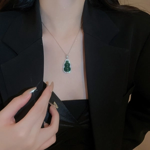 Detail of silver gourd pendant with dark green gemstone and zircon on model neck