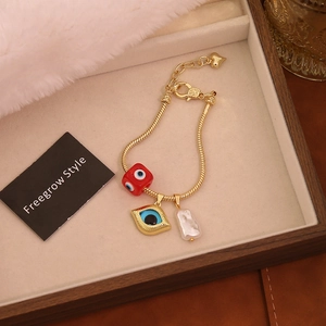 Detail of 18K gold snake chain bracelet with evil eye pendant and baroque pearl charm