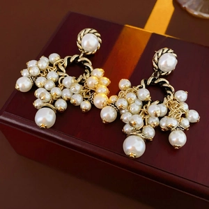 Close-up of vintage gold earrings with clustered white pearls on a red wooden box