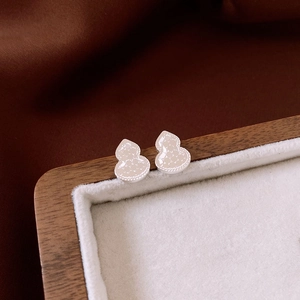 Gourd-shaped stud earrings with textured surface and beaded edge on jewelry tray