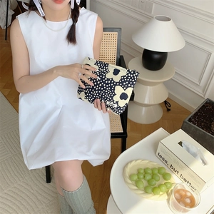 Detailed view of floral cotton makeup bag held by hand in a cozy interior setting