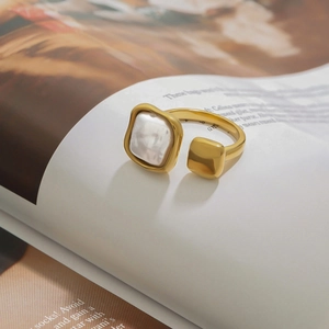 Detailed view of an open gold ring featuring an asymmetric square white pearl inlay