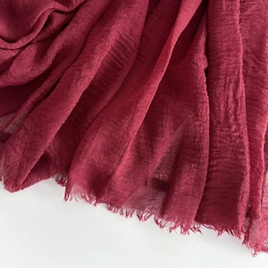 Detailed texture of wine red linen scarf with natural pleats and frayed edges