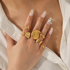 Golden ocean theme rings set featuring starfish and seashell on hand in close-up view