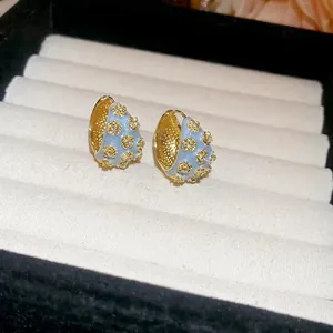 Light blue enamel C-shaped hoop earrings with gold floral patterns and cubic zirconia accents
