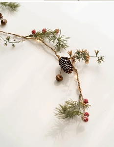 Detail of Christmas garland with pine cones, red berries and warm LED copper wire lights