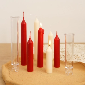 Detailed view of clear tall taper candle molds with finished red and beige wax candles