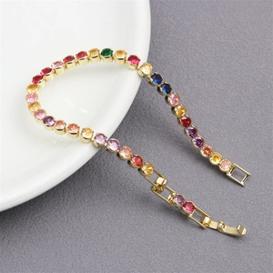 Detailed view of rainbow gold-plated tennis bracelet with multi-color zircons on white plate