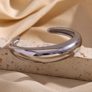 Polished silver stainless steel cuff bracelet on elegant stone stand with satin