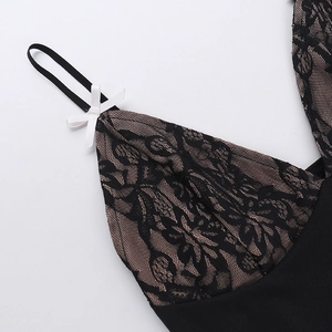 Détail du mini-haut en dentelle noire avec motifs floraux délicats et nœud blanc