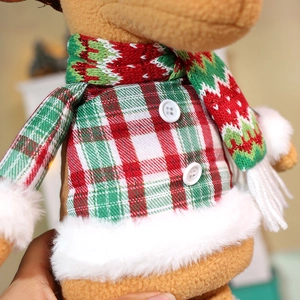 Detail of plush Christmas deer doll featuring red plaid coat and knit scarf textures