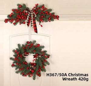 Detail of Christmas wreath and swag with red berries and plaid bows on white door