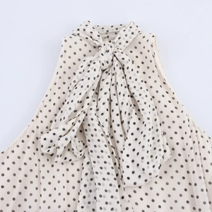 Detail of elegant cream halter dress featuring black polka dots and a large neck bow tie