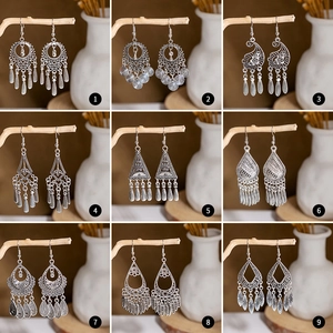 Nine pairs of vintage bohemian tassel earrings in antique silver finish displayed on wood
