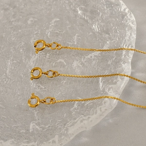 Three elegant gold-plated stainless steel chains with spring ring clasps on glass