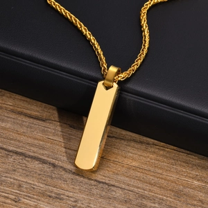 Close-up of golden stainless steel vertical bar pendant on wheat chain with black leather background