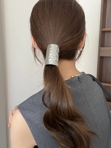 Macro detail of silver ponytail hair clip featuring hammered metallic texture on model