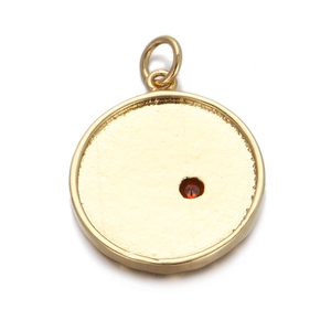 Macro shot of gold circular pendant with red gemstone and textured metal finish