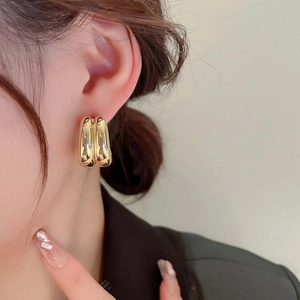 Minimalist double-tube gold hoop earrings worn by a model in a clean lifestyle shot
