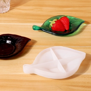 Détail du moule en silicone en forme de feuille et plateaux en résine sur surface en bois