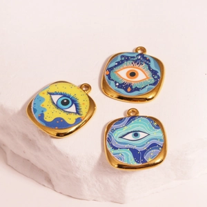 Set of three square enamel evil eye charms with gold frames on white stone background