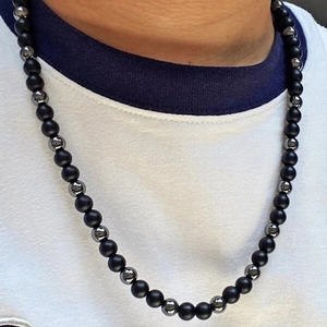Detail of beaded necklace for men featuring matte black beads and tiger eye stones