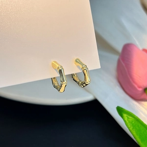 Gros plan sur des boucles d'oreilles dorées forme bambou avec finition métallique