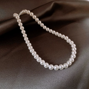 Elegant round white pearl necklace with high luster on a dark satin background