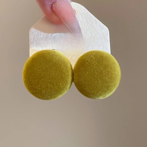 Macro view of yellow round velvet earrings with S925 silver needles on display card