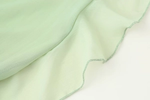 Detailaufnahme hellgrüner Chiffon-Rüschen mit professioneller Wellenkanten-Naht