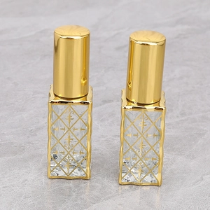 Close-up of 12ml glass perfume bottles with gold diamond patterns and metal caps