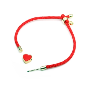 Détail du bracelet tressé rouge avec pendentif en forme de cœur et fermoir à vis doré