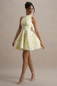 Detail of white halter neck dress featuring yellow floral print and a large back bow