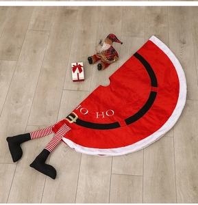Detail of red Santa Claus tree skirt with plush trim, buckle belt and striped elf legs