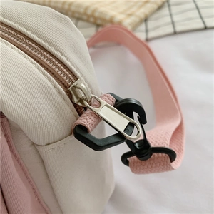 Close-up of pink canvas bag details with silver metal zipper and woven shoulder strap