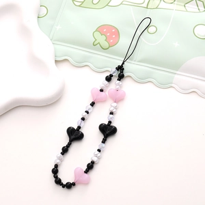 Detailed shot of pink and black heart beads with white pearls on a phone wrist strap