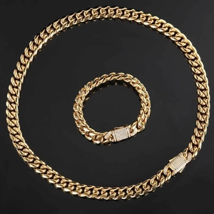 Close-up of gold Cuban chain jewelry set with diamond-encrusted spring clasps on black surface