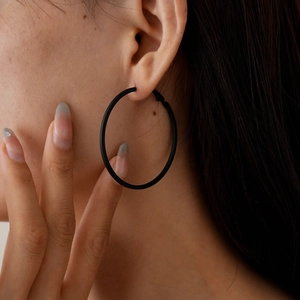 Close-up of minimalist black geometric leather round hoop earrings on a female model