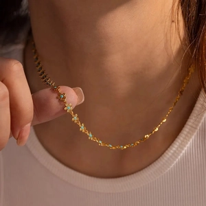 Close-up of a gold bohemian necklace with blue stone flowers worn on a neck