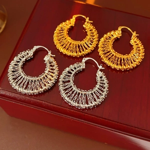 Vue détaillée de boucles d'oreilles rondes tressées en finitions or et argent polies