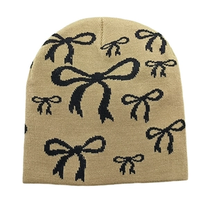 Close-up of khaki knit beanie with black bow patterns and soft wool texture detail