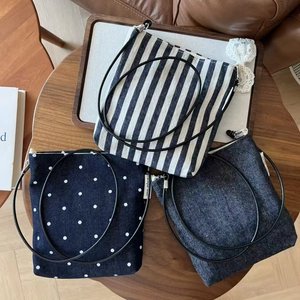 Three minimalist striped and denim crossbody mini bags for cell phones on a wooden table