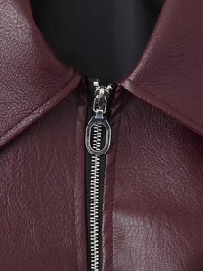 Macro detail of wine red faux leather jacket collar and metallic zipper texture