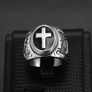 Macro detail of silver vintage cross embossed ring with black base on textured display stand