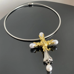 Close-up of vintage mixed metal cross pendant with four baroque pearls on black background